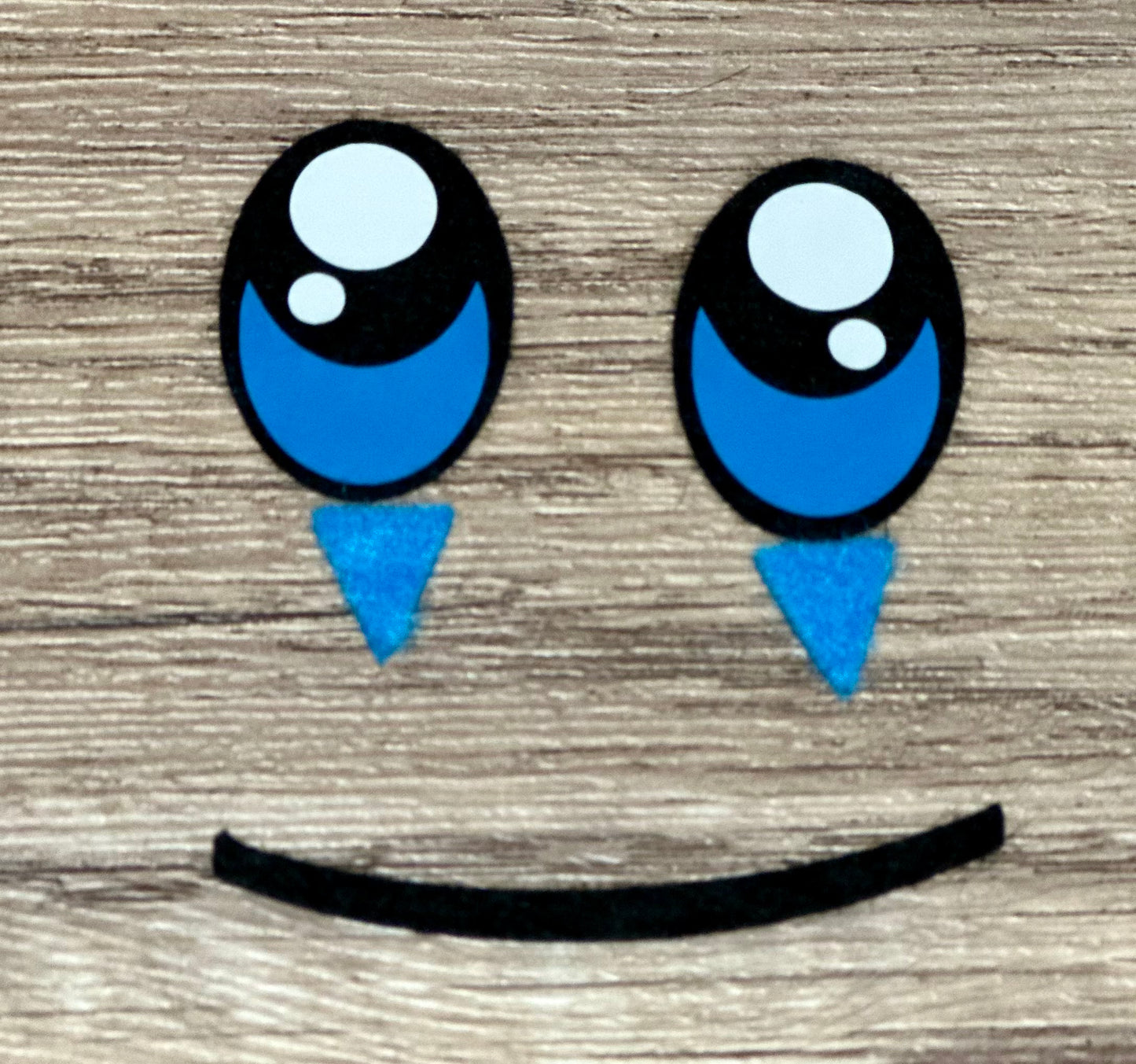 Cartoon face with blue eyes and a smile on a wooden background
