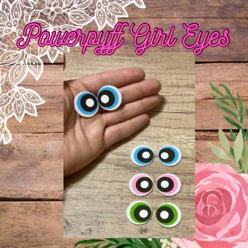 A set of crochet eyes for crafting, displayed on a hand holding three eyes with varying colors and patterns, with a floral background.